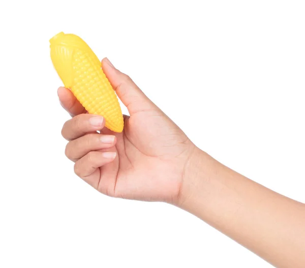 Рука тримає кукурудзу пластикової іграшки ізольовано на білому тлі — стокове фото