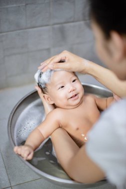 Anne tarafından havuzda yıkanan yeni doğmuş bir bebek.