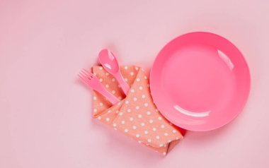 Pink color plastic plate with plastic spoon, fork and pink polka