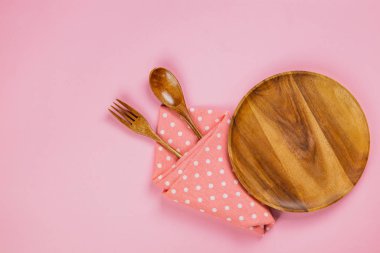 wood plate with spoon, fork and pink polka dot cloth napkin on p