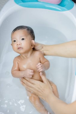 Anne tarafından havuzda yıkanan yeni doğmuş bir bebek.