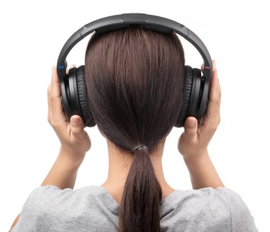 Beyaz tişörtlü bir kadın kulaklıkla müzik dinliyor. 