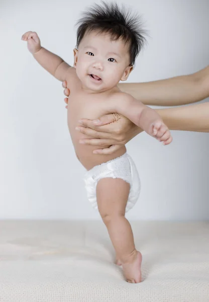 Petit bébé debout avec l'aide de la mère — Photo