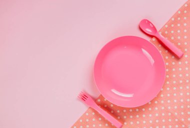 Pink color plastic plate with plastic spoon, fork and pink polka