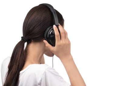 Beyaz tişörtlü bir kadın kulaklıkla müzik dinliyor. 