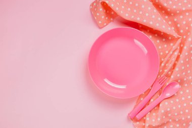 Pink color plastic plate with plastic spoon, fork and pink polka