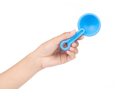 El ele tutuşan küçük plastik oyuncak kürek beyaz bir sırt üzerinde izole edilmiş.