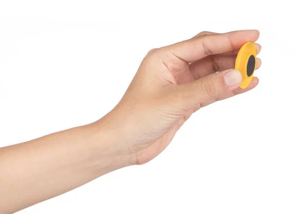 Рука держит желтый круглый пластиковый магнит изолирован на белом фоне — стоковое фото