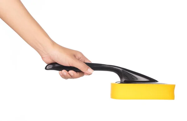 Dłoń trzymająca żółtą gąbkę z czarnym plastikowym uchwytem izolowanym o — Zdjęcie stockowe