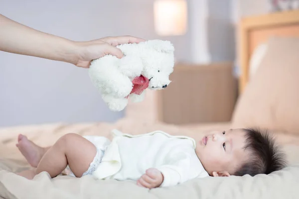 Bébé regardant Main tenant jouet coloré ours en peluche au-dessus de bébé . — Photo
