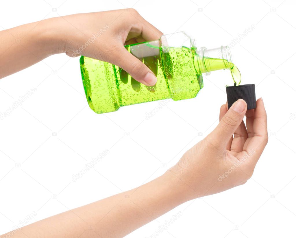 Hand pouring water mouthwash from bottle in to cap isolated on w