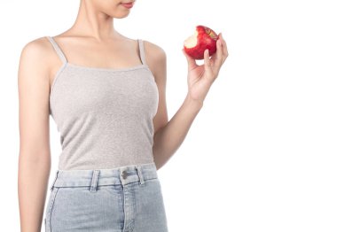 woman in grey tank top and jeans eating one red apple isolated o