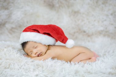 Yeni doğmuş bebek şirin kırmızı Noel Baba şapkası takıyor. Huzur içinde uyuyor.