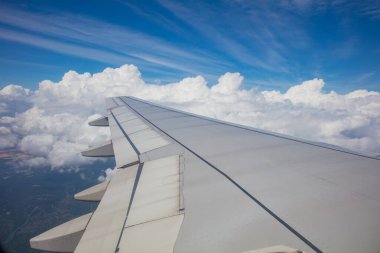 Wing of airplane flying with blue sky and clouds