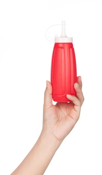 Рука тримає пляшку томатного соусу ізольовано на білому тлі — стокове фото
