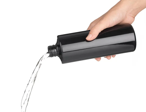 Hand gießt Wasser aus schwarzer Flasche isoliert auf weißem Backgro — Stockfoto