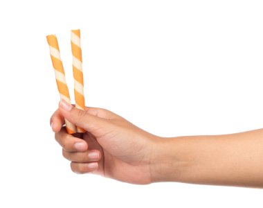 El ele tutuşan çizgili gofret ruloları beyaz arka planda portakalla izole edilmiş.