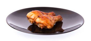 Kızarmış tavuk budu beyaz arka planda izole edilmiş bir tabakta.