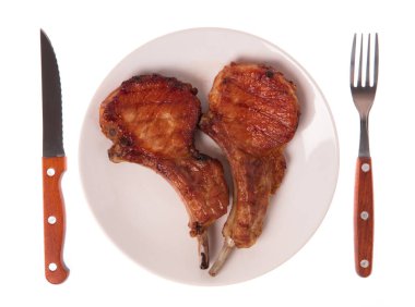 Izgara domuz kaburgası. Çatal ve bıçakla birlikte beyaz arka planda.