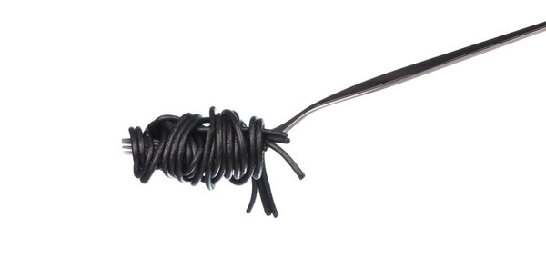 рулон черные спагетти на ложке изолированы на белом фоне
