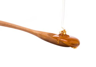 Beyaz arka planda izole edilmiş bir kaşıktan damlayan bal.