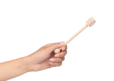 Beyaz arka planda izole edilmiş bal için ahşap kepçeyi tutan el.