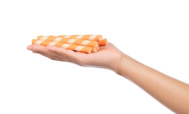 El ele tutuşan çizgili gofret ruloları beyaz arka planda portakalla izole edilmiş.