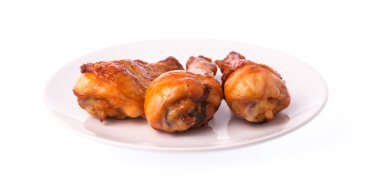 Kızarmış tavuk budu beyaz arka planda izole edilmiş bir tabakta.