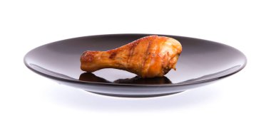 Kızarmış tavuk budu beyaz arka planda izole edilmiş bir tabakta.