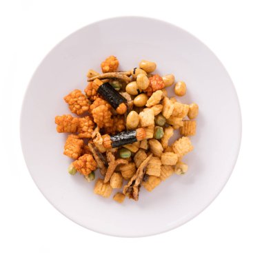 Beyaz arka planda izole edilmiş tabakta pirinç kraker, fındık ve kurutulmuş balık karışımı.