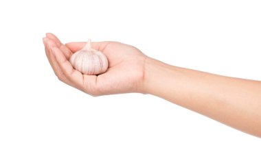 Beyaz arka planda sarımsak tutan el.