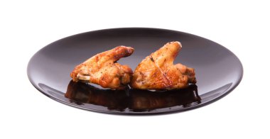 Siyah tabakta kızarmış tavuk kanadı. Beyaz arka planda izole edilmiş.