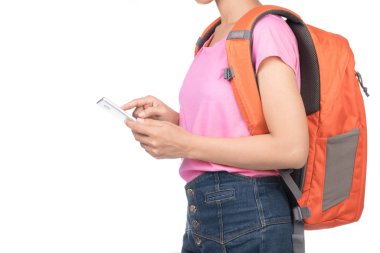 Beyaz arka planda izole edilmiş cep telefonu kullanan boş pembe tişört, kot pantolon ve sırt çantası giyen bir kadın..