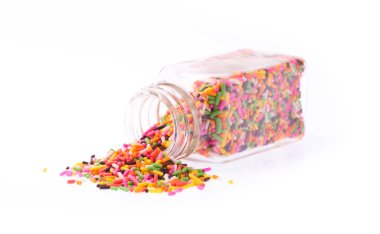 Beyaz arka planda izole edilmiş cam bir şişeden dökülen renk şekeri.