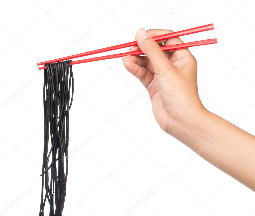 Hand holding chopsticks, eating black spaghetti isolated on white background