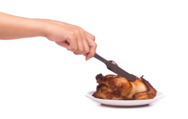 Kızarmış tavuk, beyaz arka planda izole edilmiş bir tabakta bıçak ve çatalla kesiliyor.