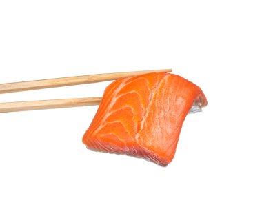 Dilimlenmiş çiğ somonu beyaz arka planda izole edilmiş çubuklarla tutmak