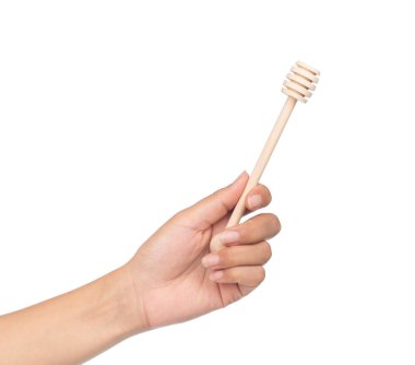 Beyaz arka planda izole edilmiş bal için ahşap kepçeyi tutan el.