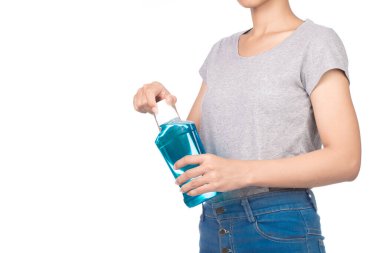 Boş gri tişört giyen bir kız, beyaz arka planda izole edilmiş bir gargara şişesi tutan bir kot pantolon..