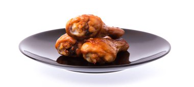 Kızarmış tavuk budu beyaz arka planda izole edilmiş bir tabakta.