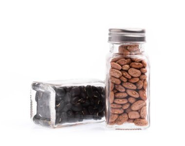 Beyaz arka planda izole edilmiş bir şişe fasulye ve siyah fasulye.