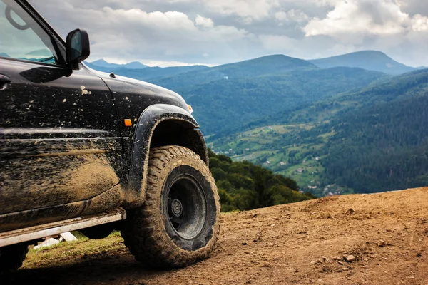 Dağlar Road arabaya. Kirli tekerleği ile SUV dağın tepesinde duruyor. Karpatlar, Ukrayna'da araba ile seyahat