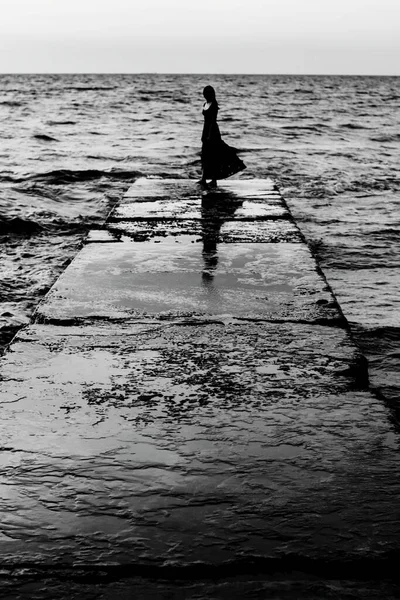 桟橋にいる少女のシルエット ノスタルジックな白黒写真 憂うつな気分 荒海の風景 — ストック写真