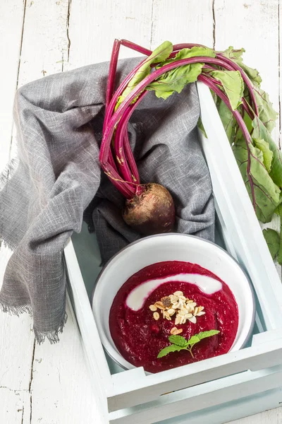 beet soup in a white bowl on wooden surface