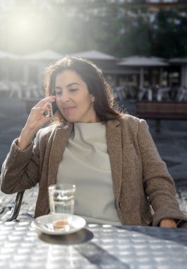 Genç, güzel, gülümseyen kadın cep telefonuyla konuşuyor. 