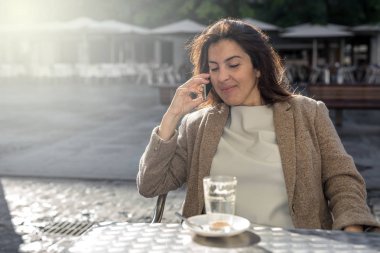 Genç, güzel, gülümseyen kadın cep telefonuyla konuşuyor. 