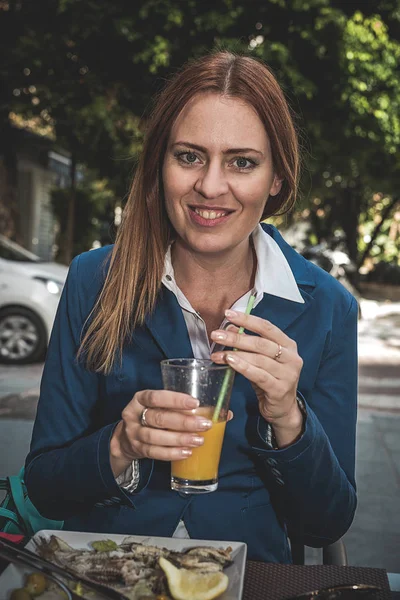 Blonde jonge vrouw eten buiten in de straat — Stockfoto