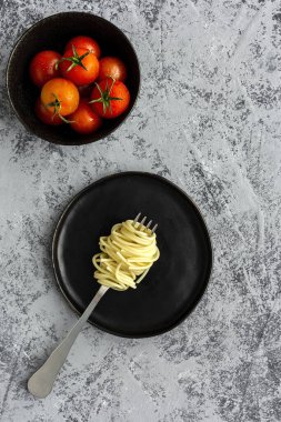 Domates ve fesleğen soslu ev yapımı spagetti, yukarıdan gri arka planda görünüyor. İtalyan pastası. Düz yatıyordu..