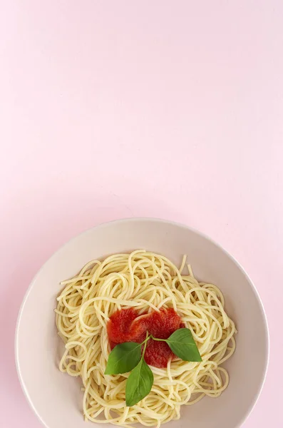 自家製スパゲティトマトソースとバジルソース ピンクの背景に上から見た イタリアのパスタフラットレイ — ストック写真