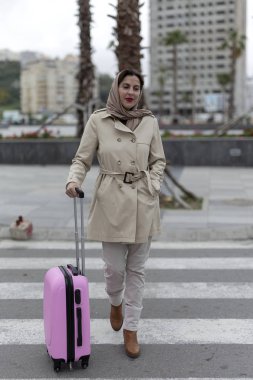 Başörtüsü ve bavulu olan çekici bir Arap kadın istasyona doğru yürüyor.
